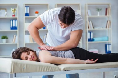 Genç doktor kayropraktik uzmanı kadın hastaya masaj yapıyor.