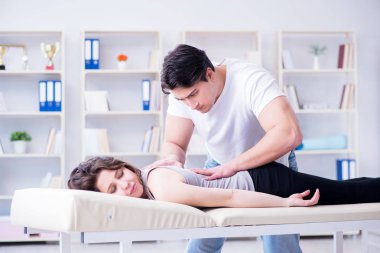 Genç doktor kayropraktik uzmanı kadın hastaya masaj yapıyor.