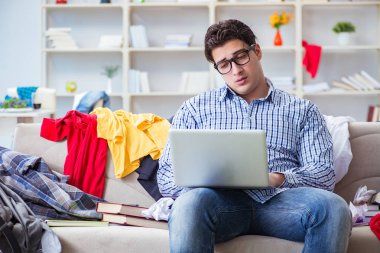 Genç adam dağınık bir odada çalışıyor.