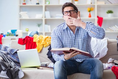 Genç adam dağınık bir odada çalışıyor.