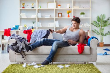 Genç adam dağınık bir odada çalışıyor.