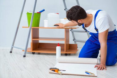 Tamirci, duvar kağıdıyla evde tadilat yapıyor.