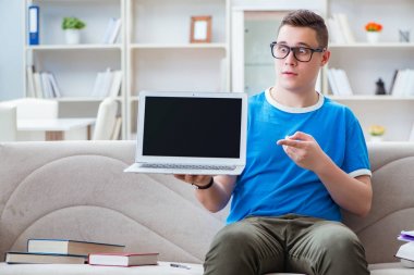 Sınavlara hazırlanan genç öğrenci kanepede ders çalışıyor.