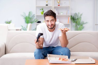 Pizza yiyen adam evde yemek yiyor, dinleniyor.