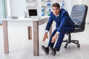 Genç işadamı iş yerinde spor yapıyor.