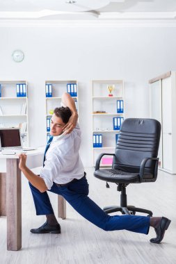 Genç işadamı iş yerinde spor yapıyor.