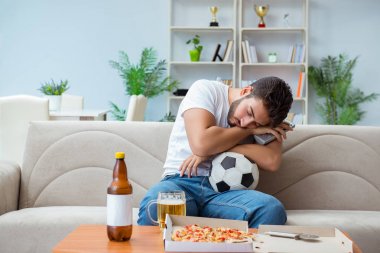 Pizza yiyen adam evde yemek yiyor, dinleniyor.