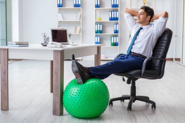 Genç işadamı iş yerinde spor yapıyor.