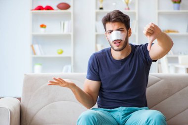 Genç adam estetik cerrahi burnundan sonra evde iyileşiyor.