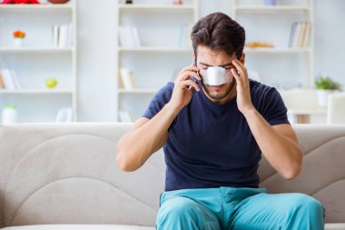 Genç adam estetik cerrahi burnundan sonra evde iyileşiyor.