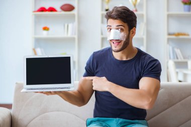 Genç adam estetik cerrahi burnundan sonra evde iyileşiyor.