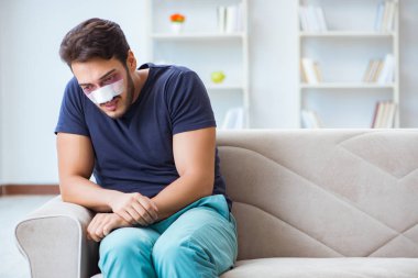 Genç adam estetik cerrahi burnundan sonra evde iyileşiyor.