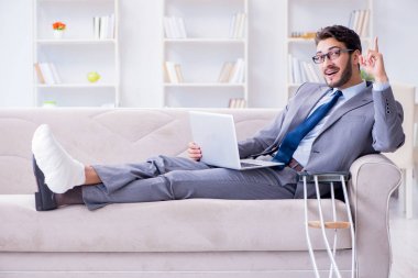 Koltuk değneği ve kırık bacağı olan bir iş adamı.