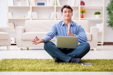Genç yakışıklı adam evde yerde oturuyor.