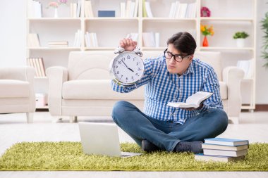 Genç yakışıklı adam evde yerde oturuyor.