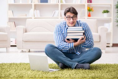 Genç yakışıklı adam evde yerde oturuyor.