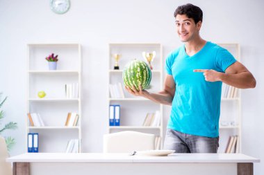 Evde karpuz yiyen bir adam.