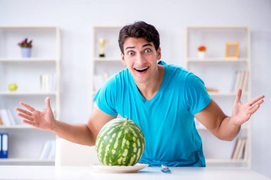 Evde karpuz yiyen bir adam.