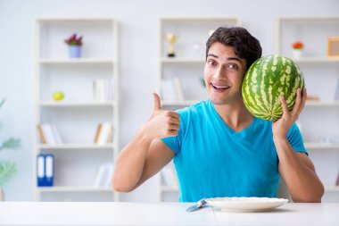 Evde karpuz yiyen bir adam.