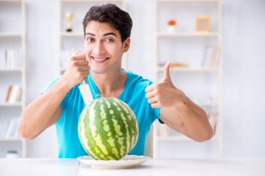 Evde karpuz yiyen bir adam.