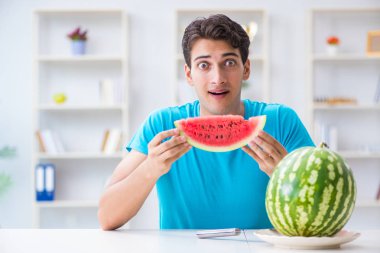 Evde karpuz yiyen bir adam.