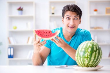 Evde karpuz yiyen bir adam.