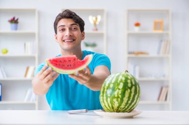 Evde karpuz yiyen bir adam.