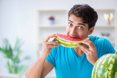 Evde karpuz yiyen bir adam.
