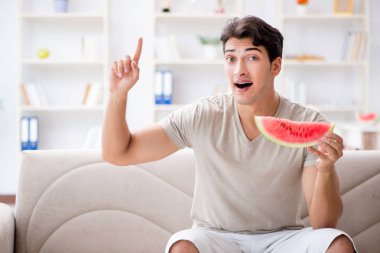Evde karpuz yiyen bir adam.