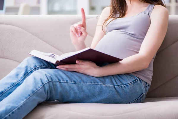Zwangere vrouw met een buik zittend op een bank thuis — Stockfoto