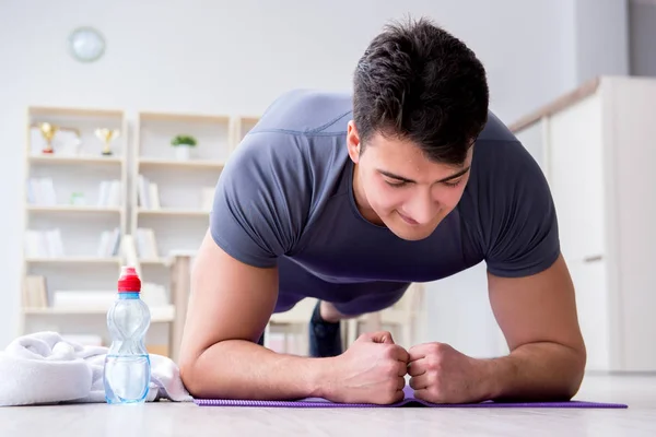 Giovane uomo che esercita a casa in sport e stile di vita sano con — Foto Stock