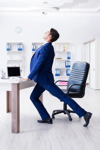 Joven empresario haciendo deporte estiramiento en el lugar de trabajo —  Fotos de Stock