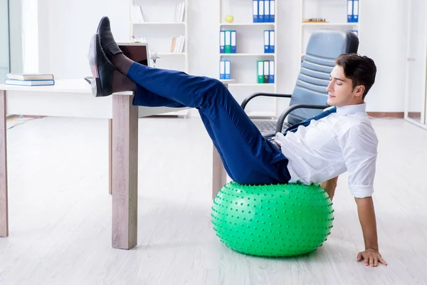 Young businessman doing sports stretching at workplace — Stock Photo, Image