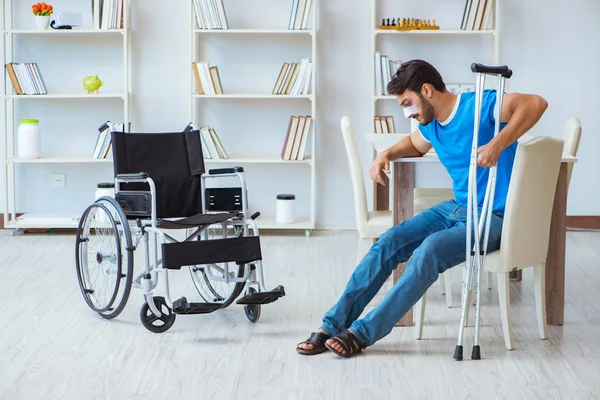 Young man recovering after surgery at home with crutches and a w — Stock Photo, Image