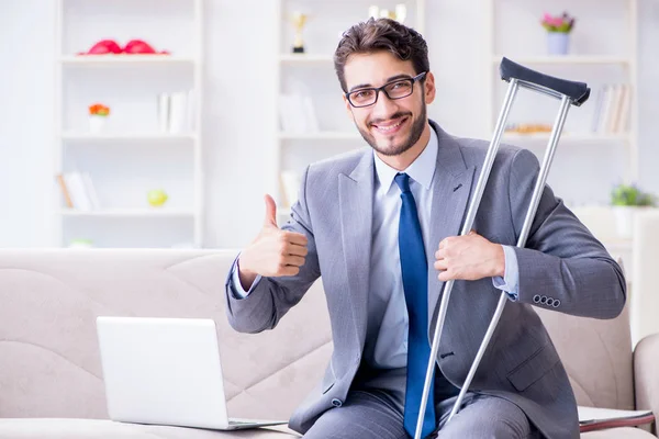 Empresario con muletas y pierna rota en casa trabajando —  Fotos de Stock