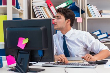 Ofiste kitap ve kağıtlarla çalışan bir işadamı.