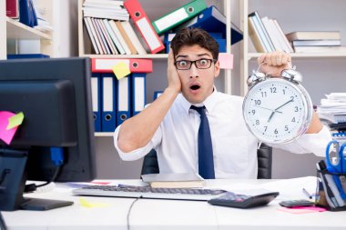 Ofiste kitap ve kağıtlarla çalışan bir işadamı.