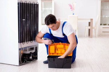 Tamirci müteahhit DIY konseptinde buzdolabını tamir ediyor.