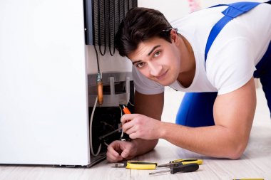 Tamirci müteahhit DIY konseptinde buzdolabını tamir ediyor.