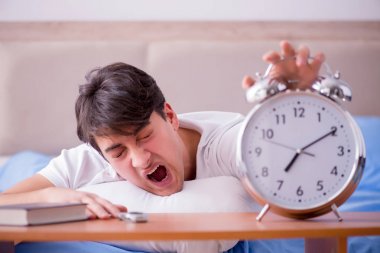Yataktaki adam alarm yüzünden uykusuzluk çekiyor.