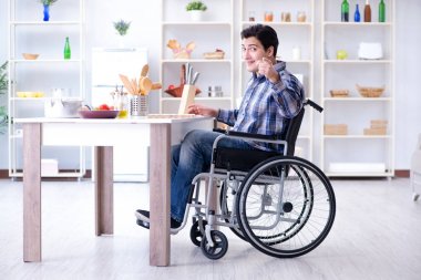 Engelli genç koca mutfakta çalışıyor.