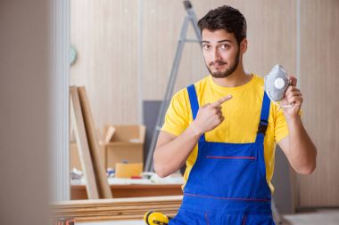 Genç tamirci marangoz odun kesiyor.