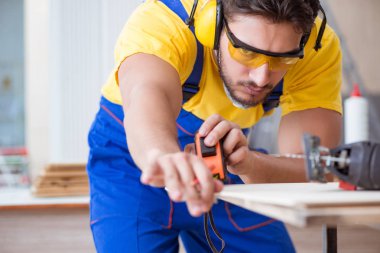 Genç bir marangoz dairesel testereyle odun kesiyor.