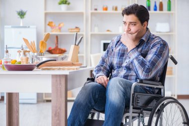 Engelli genç koca mutfakta çalışıyor.