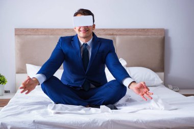 Yatak odasında sanal gerçeklik kulaklığı takan bir iş adamı.