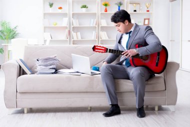 Evde gitar çalan bir iş adamı.
