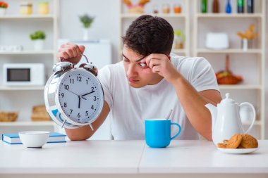 Çalar saati olan bir adam kahvaltıda uyuyakalıyor.