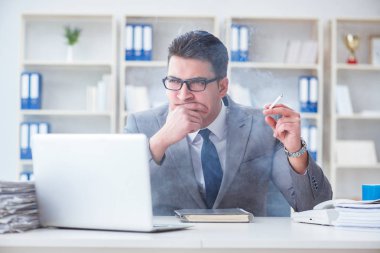 İşadamı ofisinde sigara içiyor.