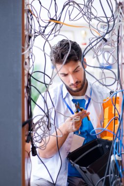 Elektrik teknisyeni tamir konseptinde kabloları çözmeye çalışıyor.