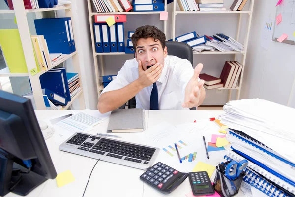 Zakenman werkzaam in het kantoor met stapels boeken en papieren — Stockfoto